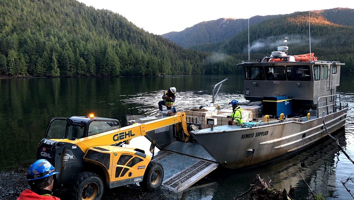 A Remote Made Easy landing craft being unloaded on an Alaskan shoreline with a forklift at sunset.